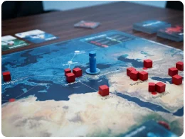 Plansza do gry strategicznej przedstawiająca mapę świata z czerwonymi kostkami infekcji